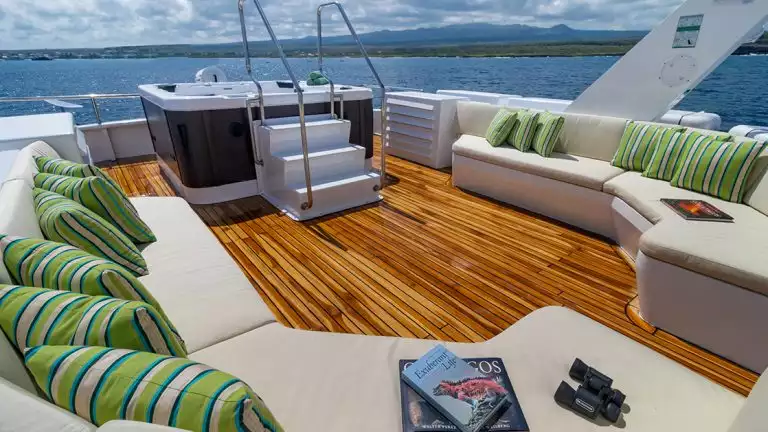 The Sun Deck Jacuzzi aboard Galapagos Angel with bench seating around it decorated with green striped pillows.