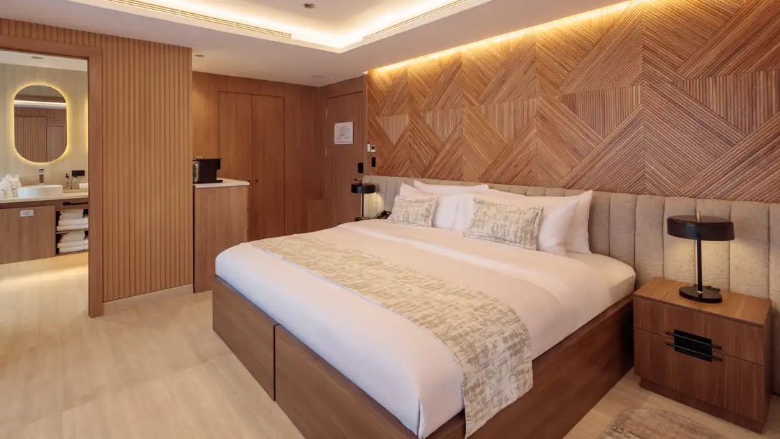 Double Suite with king bed on Hermes mega catamaran with white linens, modern furniture, wood accent walls & recessed lighting.