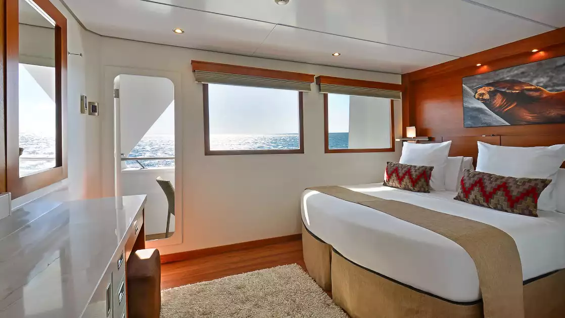 Category 5 Cabin aboard National Geographic Delfina with two windows, door to outside balcony one bed and photo above bed