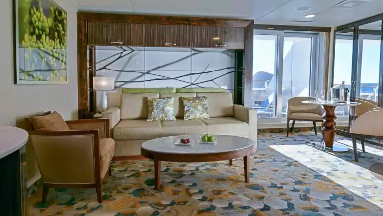 Category 7 Cabin aboard the National Geographic Gemini. Separate seating areas with sofa, coffee tables and glass door to side balcony.