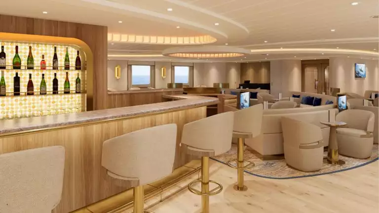 Beige interior bar aboard Nat Geo Gemini. Upholstered accent chairs with picture windows, tall tan and gold bar chairs and granite counter top.