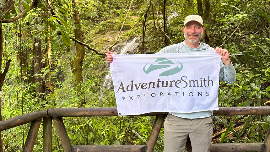 Adventure specialist holds up a white adventure smith flag in the costa rica jungle
