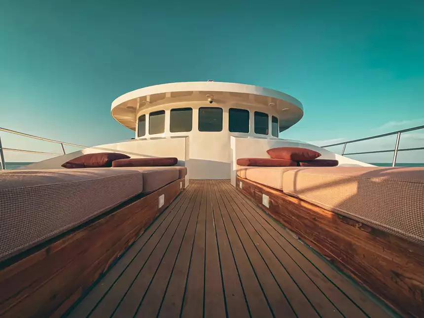 Seating area aboard small cruise ship with red cushions and wooden floors in front of the capitals look out,