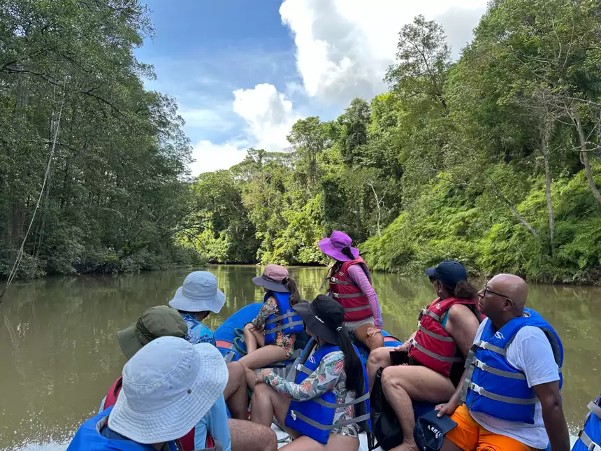 Group of travelers navigate through the costa rica jungle aboard small skiff in life jackets and hats