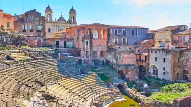 Catania, Sicily's stone amphitheater leading to a grassy stage surrounded by colorful buildings, seen on cruises to Malta.