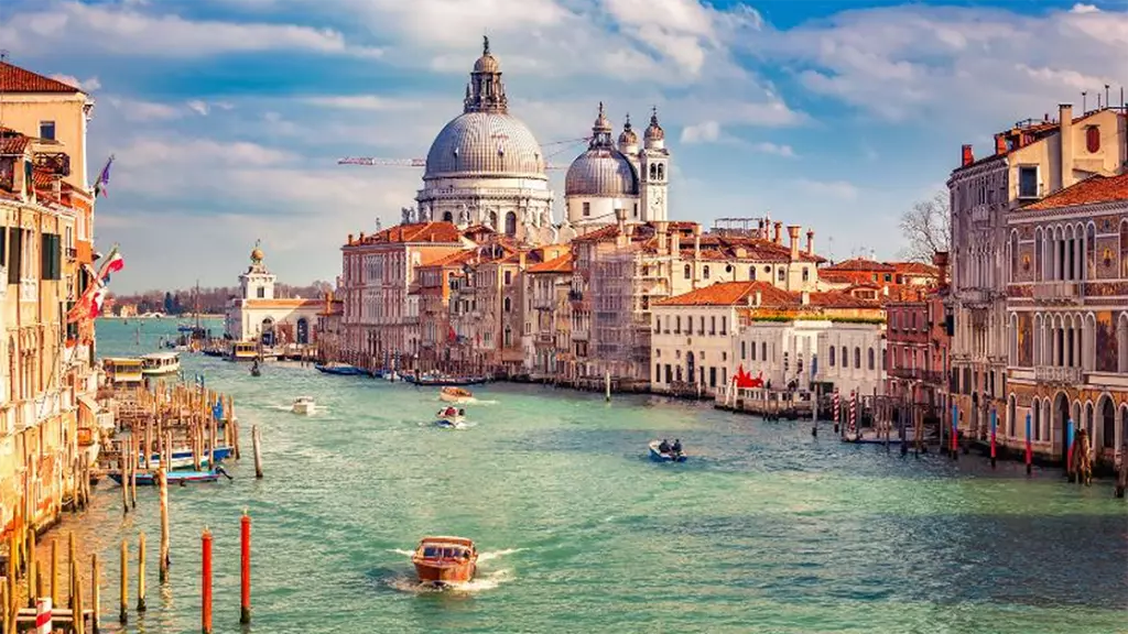 The view off a bridge in Venice viewing into the canals with boats passing by on a beautiful sunny day