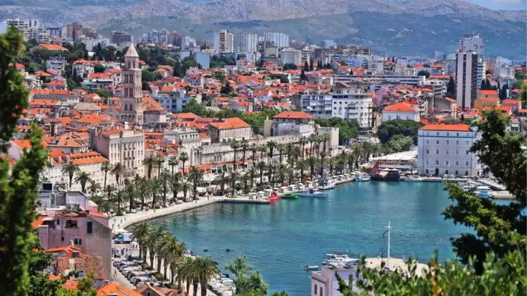 ariel view of split croatia with red roofs and white buildings and palm trees lining the water