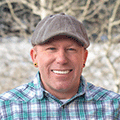 Portrait of Kiel Sprague in a plaid shirt with snowy background and a fence