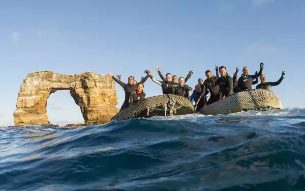 Scuba divers from the Galapagos Sky pose next to Darwins's Arch offshore Darwin Island, Galapagos, Ecuador.