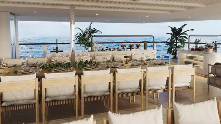 Rendering of empty long modern table with cream-colored chairs with views out to the sea aboard Paspaley Pearl cruise ship.