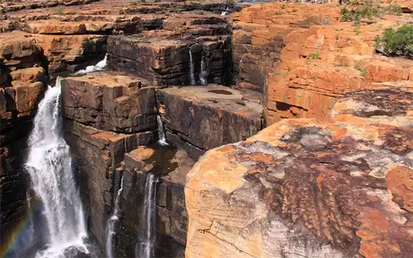 waterfall jutting out the side of a rocky cliff seen on a kimberly australia small ship cruise