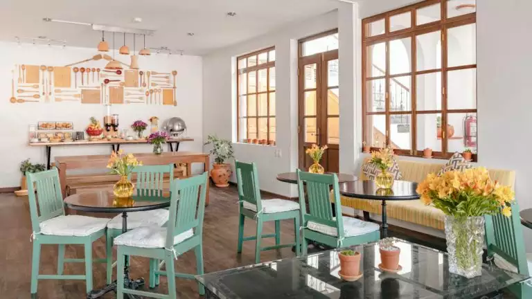 Breakfast and dining area at the Andenes Boutique hotel with green chairs and white walls, the space is clean and modern