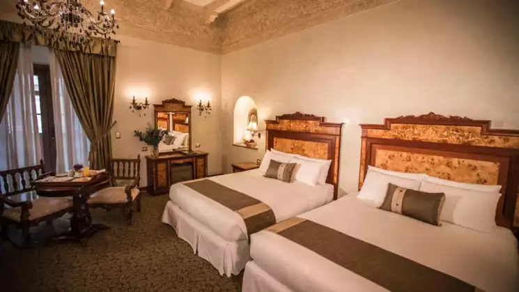 Doubled bedroom with white bed sheets and a traditional classic look at Aranwa Cusco boutique