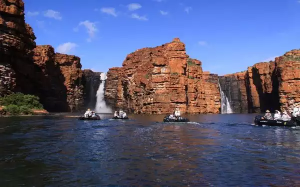 kimberly australia small ship cruise travelers in inflatable motorized rafts heading toward giant waterfalls coming out of sheer cliffs in the distance