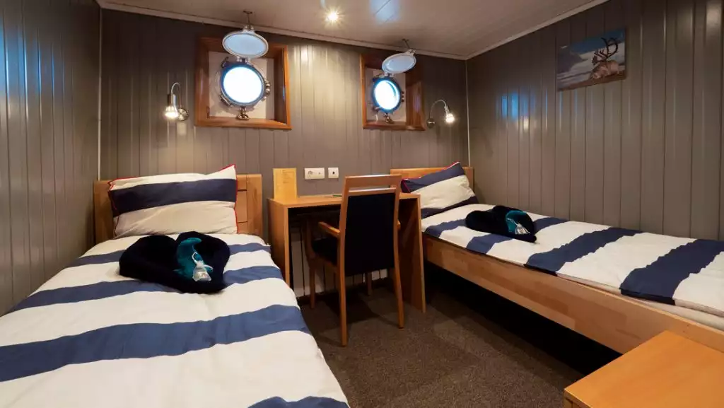 Twin cabin with portholes aboard Svojeien. Photo by: