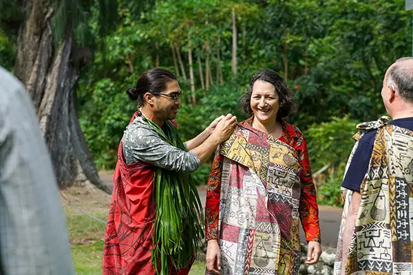 A Pacific Islands cruise passenger dressed in a colorful robe being tied by a guide on Molokai in Hawaii