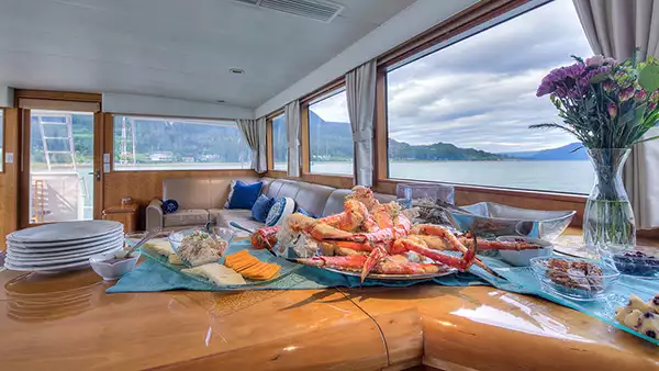 Crab legs overflow on a plate atop a wooden counter on a luxury Alaska yacht cruise