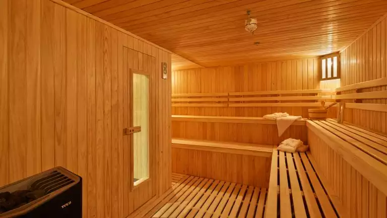 Sauna on luxury Antarctica expedition ship Magellan Explorer, with rows of wooden slat bench seating & a coal dry heater.