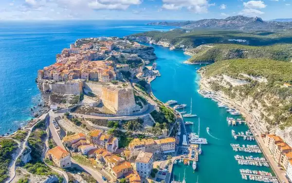 Aerial view of a small ship cruise Mediterranean port town showing boats docked and a castle on an island