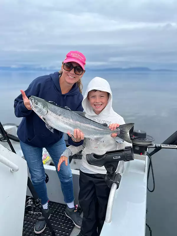 A mom and son hold a fish they caught from an Alaska charter ship