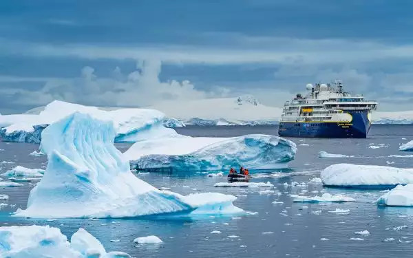 The Ship National Geographic Resolution and Zodiac exploring sculpted icebergs in Gerlache Strait, Antarctica.