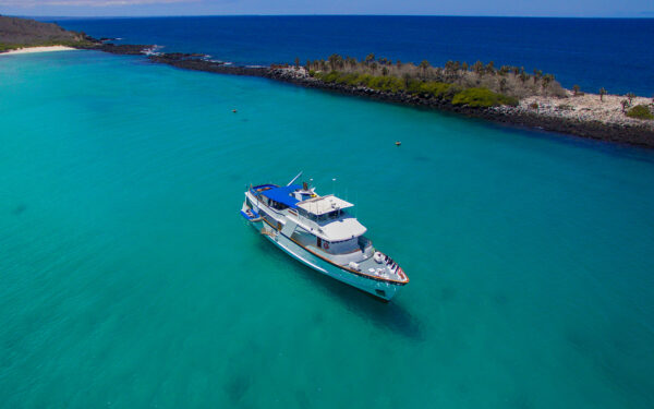 An aerial view of the Beluga galapagos private charter yacht floating in crystal clear teal water of the Galapagos Islands in Ecuador