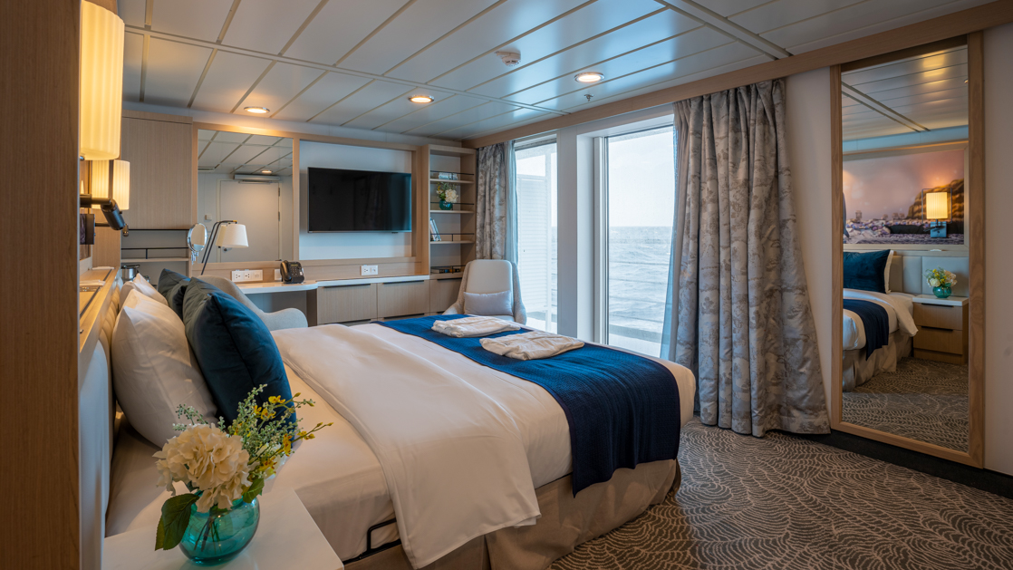 double bed aboard small ship cruise in antarctica with blue and white tones and balcony with seating