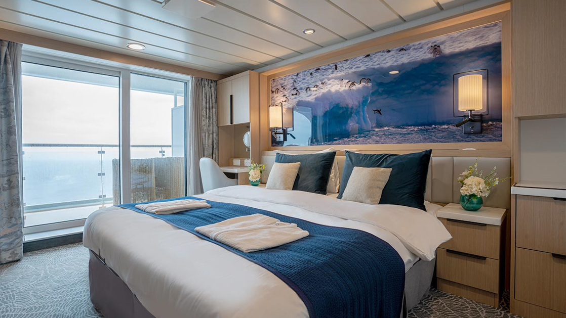 double bed aboard small ship cruise in antarctica with blue and white tones and floor to celling windows