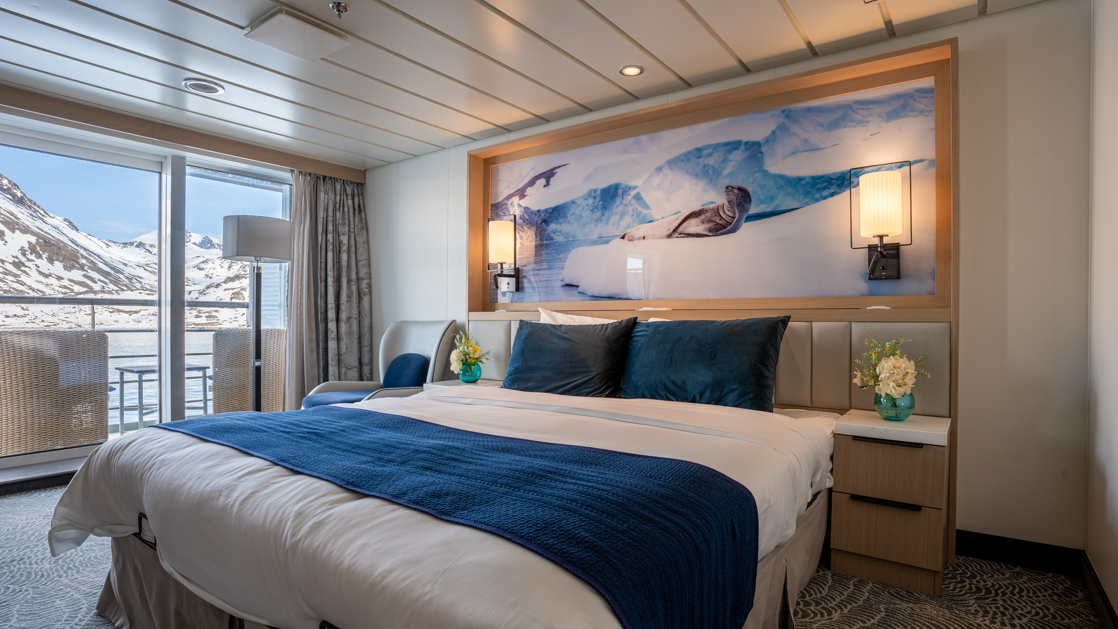 double bed aboard small ship cruise in antarctica with blue and white tones and floor to celling windows