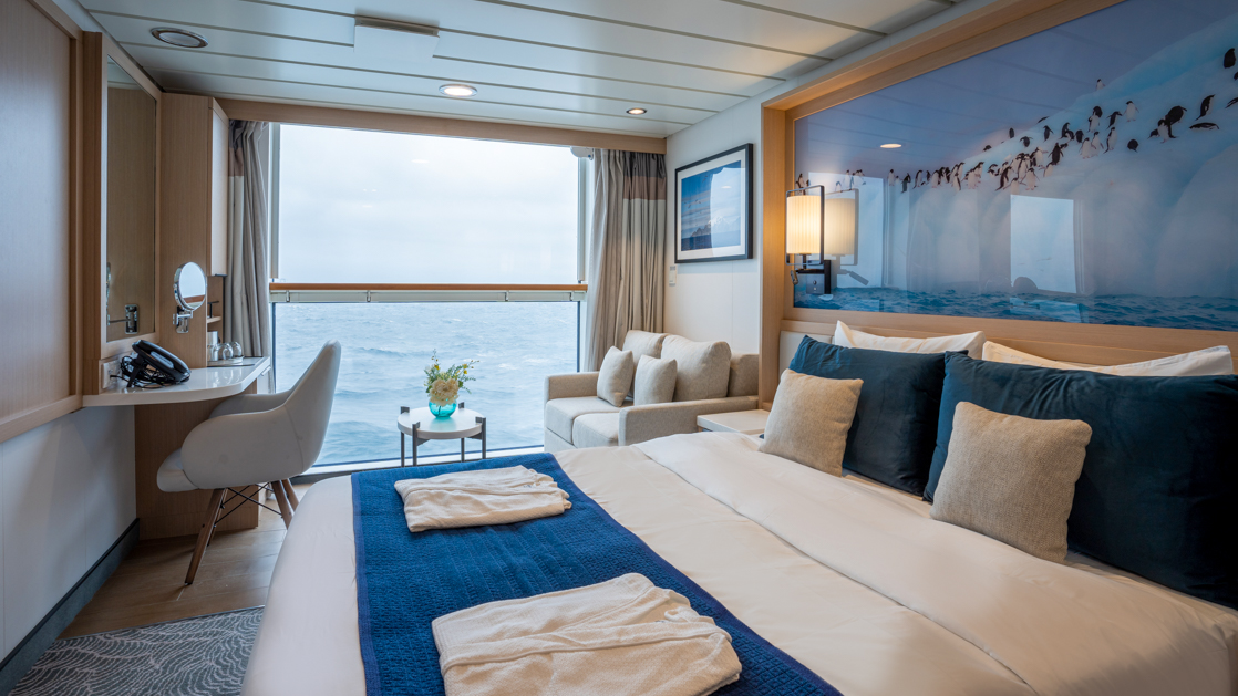 double bed aboard small ship cruise in antarctica with blue and white tones and Juliet balcony