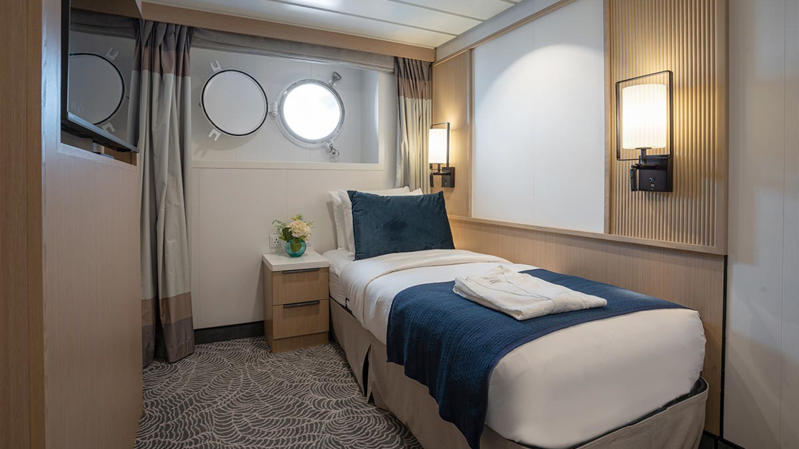single suite aboard small ship cruise in antarctica with blue and white tones and a porthole window