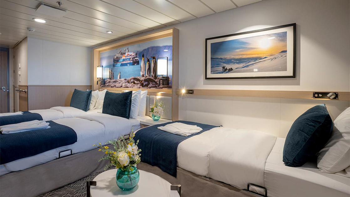 Triple bedroom aboard small ship cruise in antarctica with blue and white tones and floor to celling windows