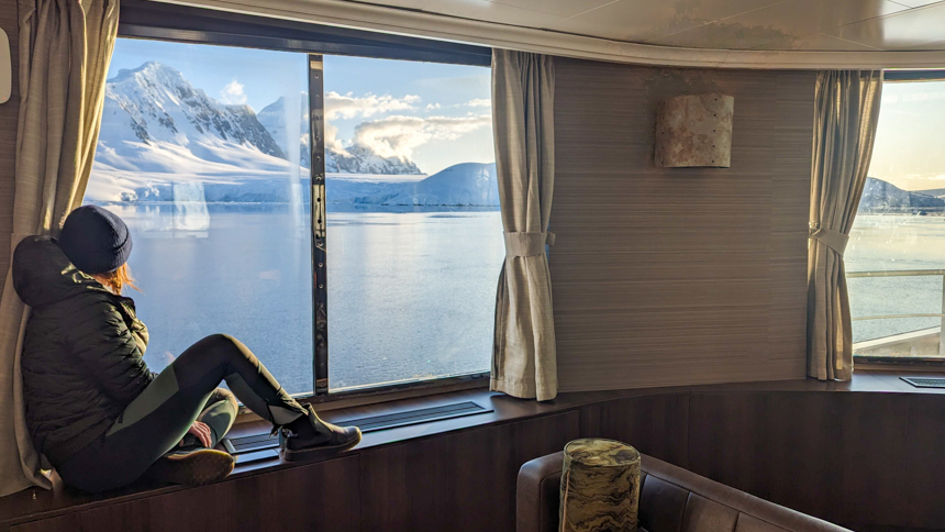 Women sitting in the window of small cruise ship Hondius as she looks out at the breathtaking mountains