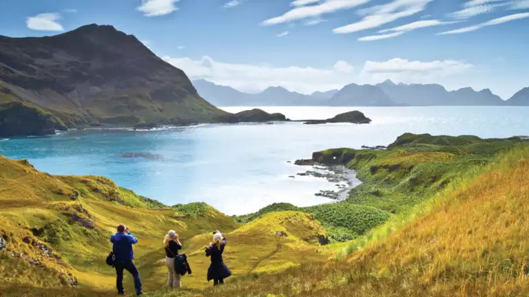 Lindblad Expeditions guests in Antarctica, South Georgia, and the Falklands hiking through the grassy hills overlooking the beautiful waterways
