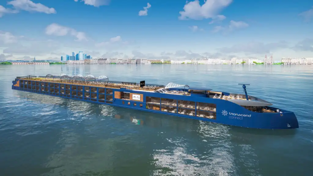 Modern blue riverboat National Geographic Connect with open-air teak top deck sits in calm sea on a sunny day in Europe.