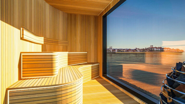 Wood sauna with 2 curved benches & hot rocks beside wall of glass aboard National Geographic Connect riverboat in Europe.