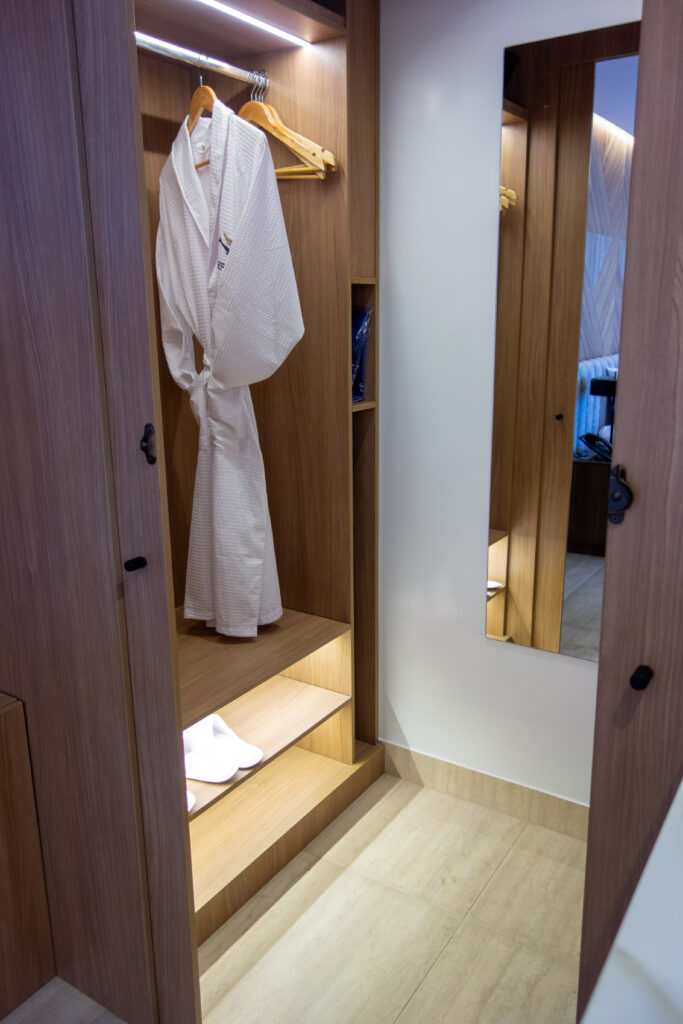 The well-lit closet of the Hermes catamaran's Double Suite showing a robe and slippers